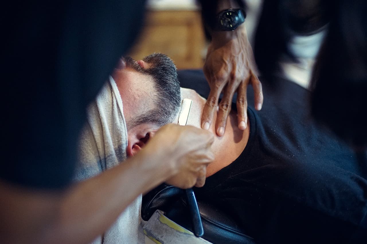 Barber shaping a customer’s beard in the chair